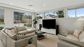 Ein modernes Wohnzimmer mit großem Fernseher, zwei Sofas und einem Couchtisch.
