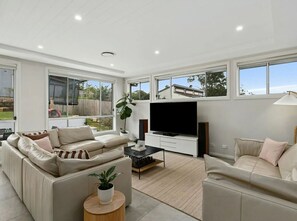 Ein modernes Wohnzimmer mit großem Fernseher, zwei Sofas und einem Couchtisch.