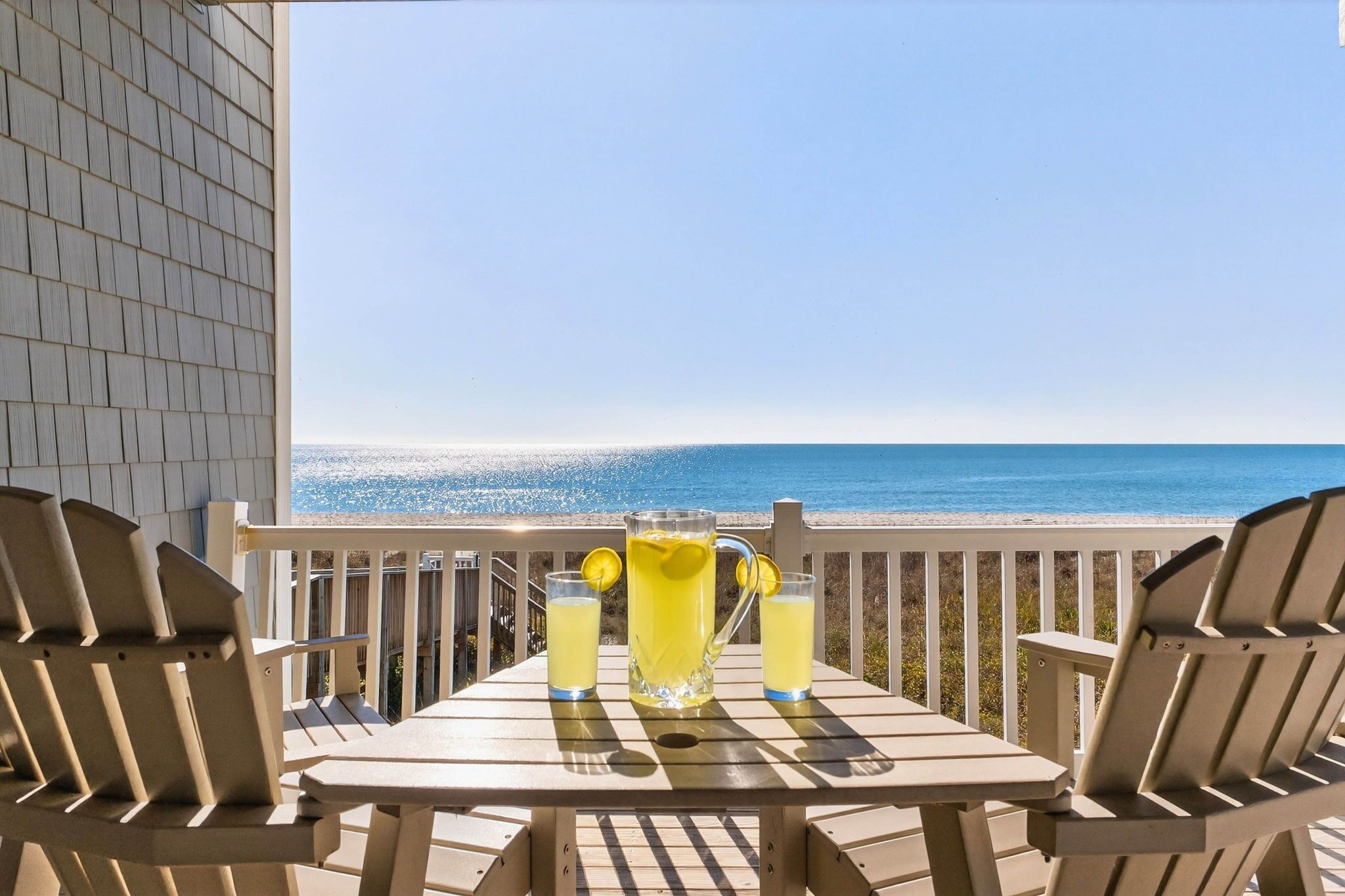 A balcony with a table and chairs overlooking a beach.