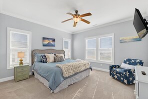 A bedroom with a bed, a nightstand, a desk, a chair, a ceiling fan, and a window with blinds. - Endless Summe, Oceanfront 8 Bedroom w/ Heated Pool (Holden Beach)