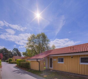 A row of single-story buildings with a red-tiled roof, a clear sky, and a sunny day. - Gemutlicher Doppelbungalow mit Garten und Terrasse im Ferienpark Mirow (Mirow)