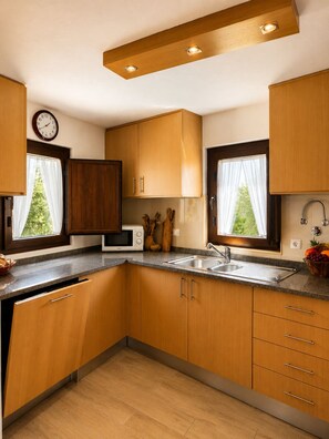 Eine moderne Küche mit Holzausstattung, einer Mikrowelle, einem Spülbecken und einem Fenster mit Vorhängen.