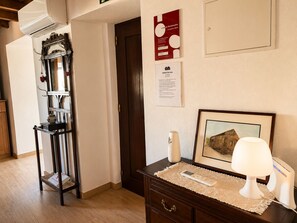 Ein Hotelzimmer mit einem Holzkapfen, einem gerahmten Bild, einer Nachttischlampe, einer Fernbedienung und einer wandmontierten Klimaanlage.