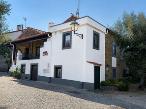 A two-story building with a stone facade, a balcony, and a cobblestone street. - Casa dos Laia | Nature, Comfort, and Tranquility (Sobreira Formosa)