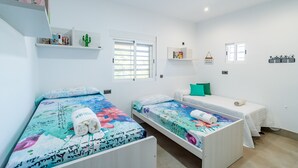 A room with two single beds, a small sofa, a cactus decoration, and a shelf with books and a sign. - Cubo's Maipa Rural House / Private pool / BBQ / Free Wi-Fi (Loja)