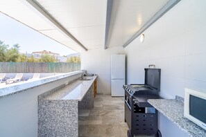 Eine kompakte Küche mit integriertem Kühlschrank, einer Spüle und einer Grillstation.