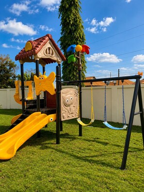 Un parque infantil con tobogán, columpios y estructura para escalar.