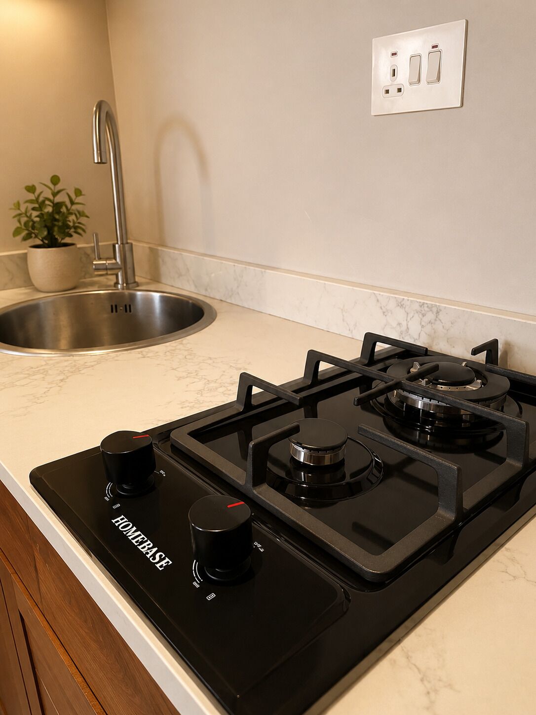 Una cucina con un piano cottura nero, un lavello e una pianta in vaso.