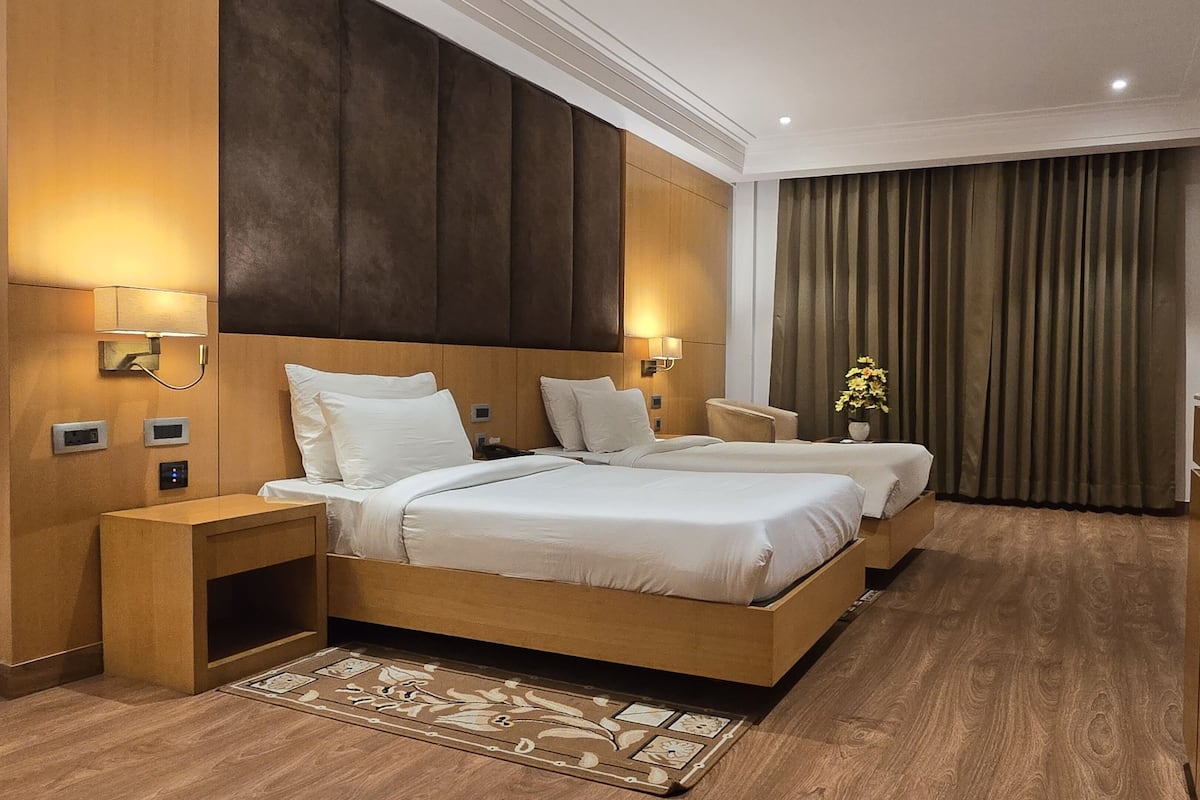 Een hotelkamer met twee bedden, een bureau, een televisie en een badkamer.