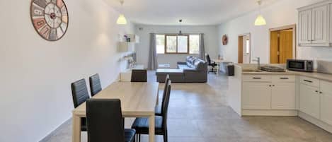 Una cocina moderna con armarios blancos, un microondas y un comedor con una mesa y sillas.