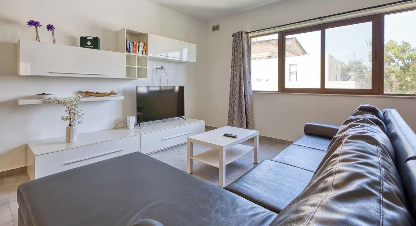 Una sala de estar moderna con un sofá, una televisión, una mesita de centro y estanterías empotradas.