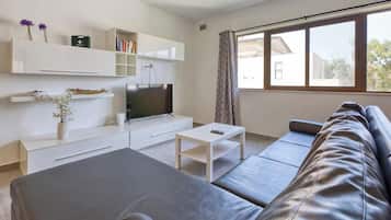 Una sala de estar moderna con un sofá, una televisión, una mesita de centro y estanterías empotradas.
