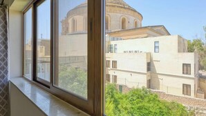 A window view of a building with a dome and a modern structure in the foreground. - Fully equipped 3BR Mosta home, Rotunda View w/WIFI (Mosta)
