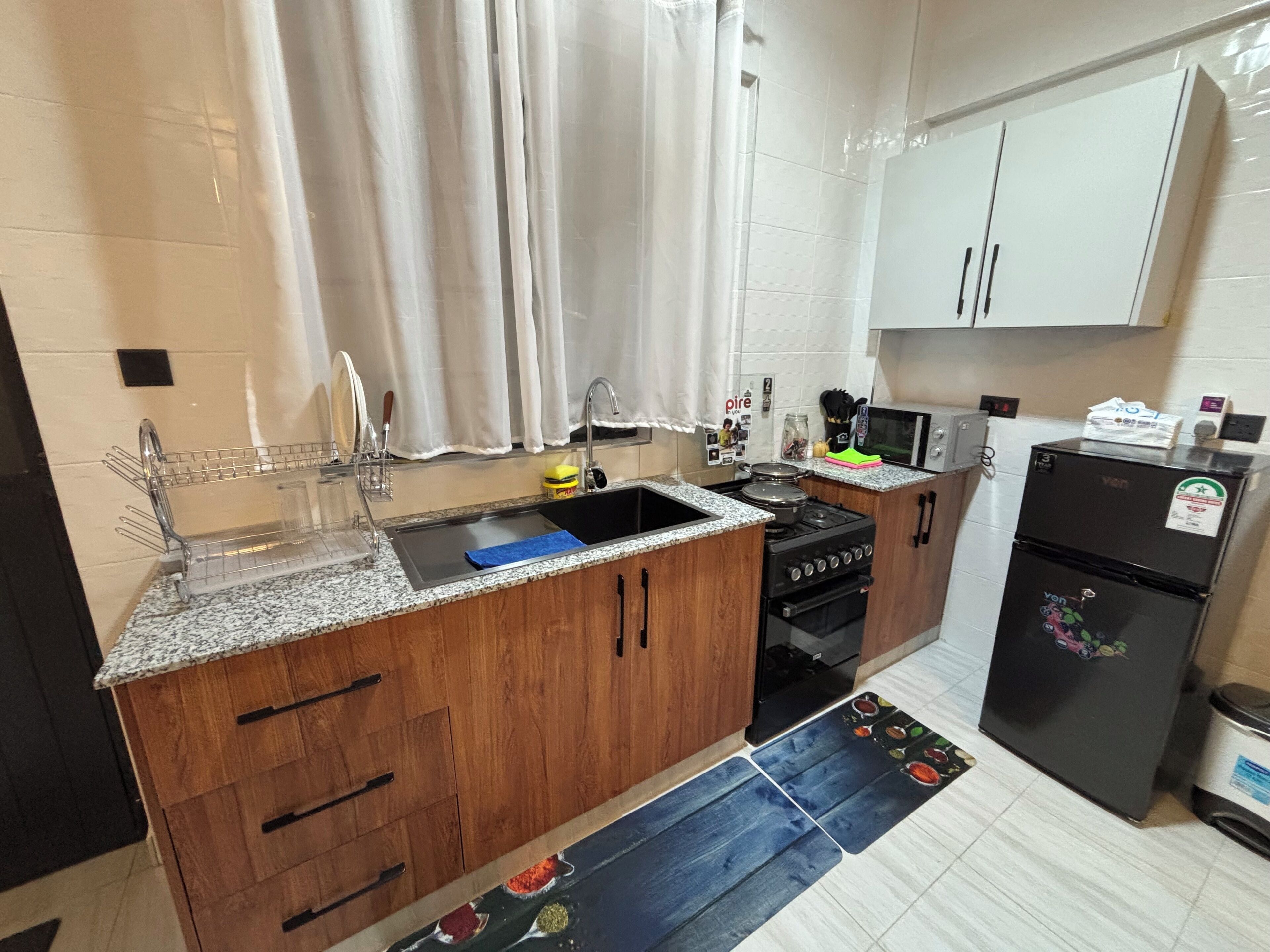Une cuisine équipée d’un évier, d’une cuisinière, d’un réfrigérateur et de meubles de rangement en bois.