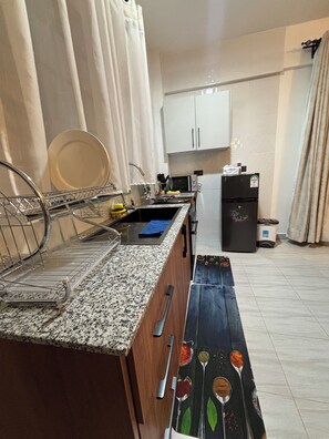 Eine Küche mit Granit Arbeitsplatte, Spüle, Mikrowelle, Kühlschrank und Mülleimer.