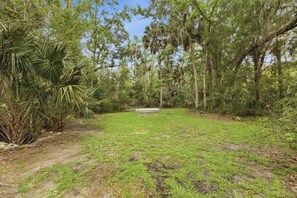 A grassy area with a bench and trees. - The Cottage at Crystal River Hideaway (Crystal River)