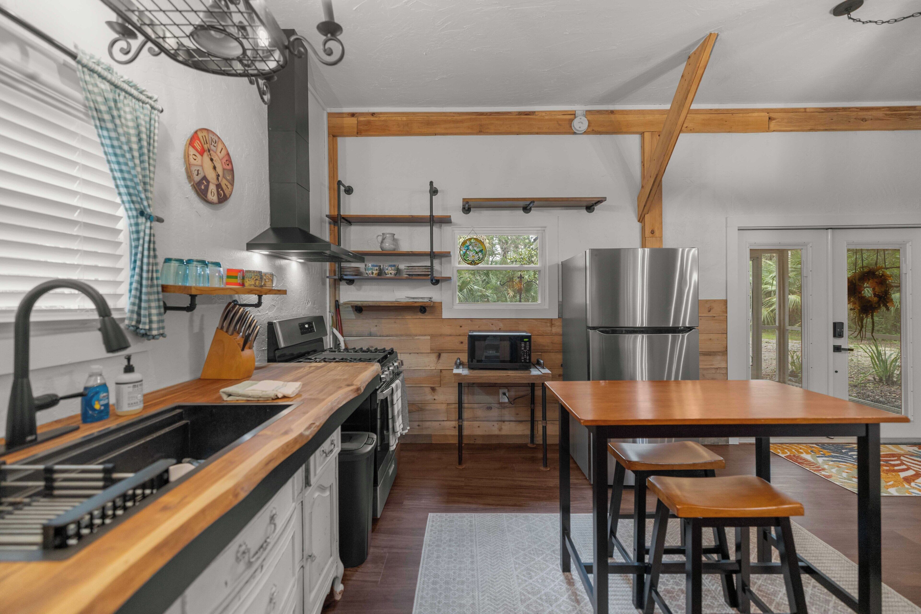 Una cocina con vigas de madera, un refrigerador de acero inoxidable, un microondas y un lavamanos.