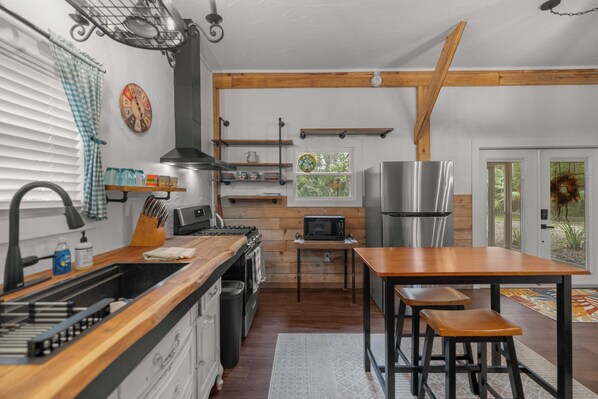 A kitchen with wooden beams, a stainless steel refrigerator, a microwave, and a sink.