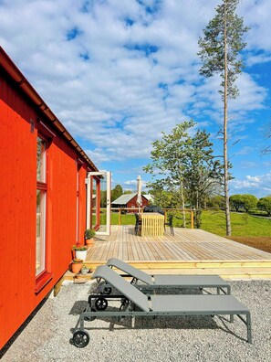 Ein rotes Gebäude mit einer Terrasse, Gartenmöbeln und einer Pergola.