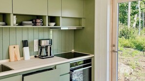 Eine moderne Küche mit grünen Schränken, einer Kaffeemaschine und einem Geschirrspüler.