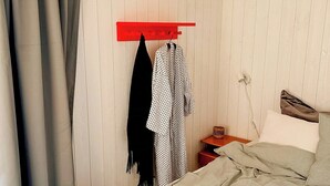 Ein Schlafzimmer mit einem Bett, einer roten Wandregal, einem Nachttisch und einer wandmontierten Steckdose.