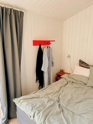 Ein Schlafzimmer mit einem Bett, einer roten Wandregal, einem Nachttisch und einer wandmontierten Steckdose.