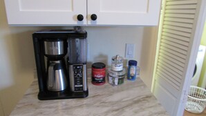 A kitchen with a coffee maker, sugar, and a container of Folgers coffee. - 3 Bedroom Home, Lots of Room Pools, golf course, Fishing Pier and Private Beach. (Micco)