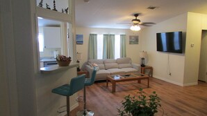 A living room with a sofa, a coffee table, a TV, and a ceiling fan. - 3 Bedroom Home, Lots of Room Pools, golf course, Fishing Pier and Private Beach. (Micco)