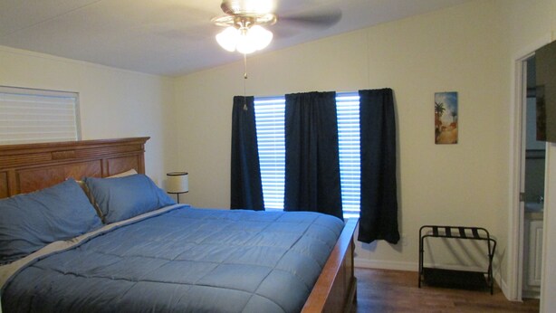 A bedroom with a bed, a ceiling fan, a window with blinds, and a nightstand. - 3 Bedroom Home, Lots of Room Pools, golf course, Fishing Pier and Private Beach. (Micco)