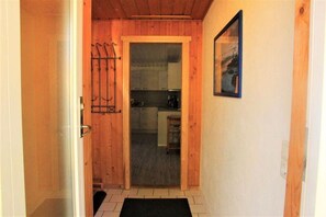 A narrow hallway with a wooden door leading to a kitchen area. - Urlaub am Wasser - Doppelbungalow mit Terrasse im Ferienpark Mirow (Mirow)