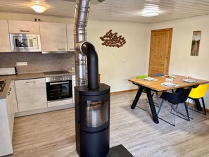 A modern kitchen with a built-in stove, a dining area with a wooden table and chairs, and a wooden door. - Urlaub am Wasser - Doppelbungalow mit Terrasse im Ferienpark Mirow (Mirow)