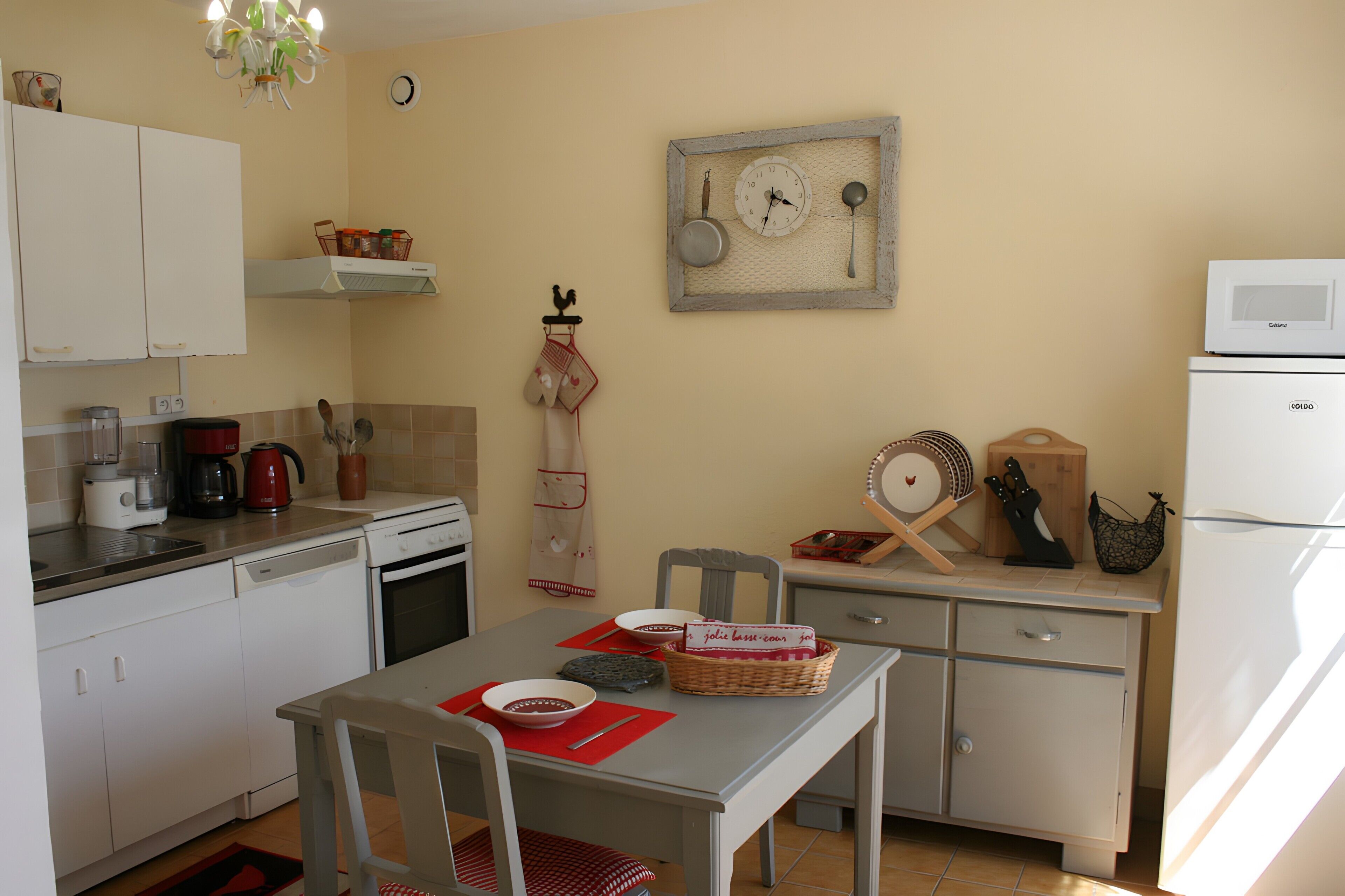 A compact kitchen with white cabinets, a dining table with chairs, a microwave, and a refrigerator.