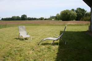 Two lawn chairs in an open grassy area with a view of trees and a building in the background. - Gîte le lit de la loire (Varennes-sur-Loire)