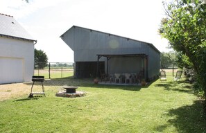 A covered outdoor seating area with chairs and a barbecue grill. - Gîte le lit de la loire (Varennes-sur-Loire)