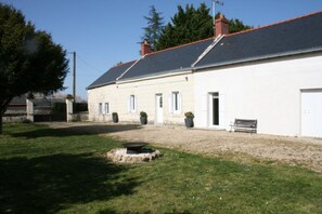 A two-story building with a gravel driveway, a bench, and potted plants. - Gîte le lit de la loire (Varennes-sur-Loire)