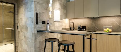A modern kitchen with a stone accent wall, a bar area with stools, and wooden cabinets.