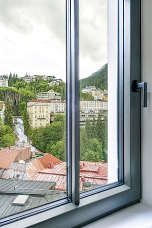 A window with a view of a cityscape, including buildings and a waterfall.