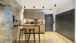 A modern kitchen with a stone accent wall, a central island with stools, and a built-in oven. - Waterfall View Penthouse · One-Bedroom (Residenz Boutique Suites (Bad Gastein))
