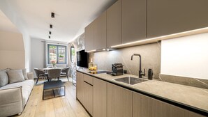 A modern kitchen with a built-in island, a dining area with a table and chairs, and a sofa. - Waterfall View Penthouse · One-Bedroom (Residenz Boutique Suites (Bad Gastein))