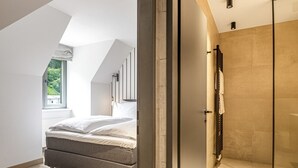 A modern bedroom with a large bed, a walk-in closet, and a view of the outdoors. - Waterfall View Penthouse · One-Bedroom (Residenz Boutique Suites (Bad Gastein))