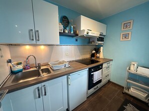 A kitchen with white cabinets, a sink, a stove, and a microwave. - Apartment with balcony, sea view - 4 guests (Cabourg)