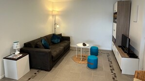 Ein modernes Wohnzimmer mit einer Couch, einer Lampe, einem Couchtisch und einem TV-Schrank.