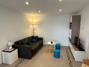 A modern living room with a sofa, a lamp, a coffee table, and a TV stand. - Apartment with balcony, sea view - 4 guests (Cabourg)