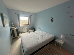 A bedroom with a bed, a nightstand, a dresser, a window, and a radiator. - Apartment with balcony, sea view - 4 guests (Cabourg)