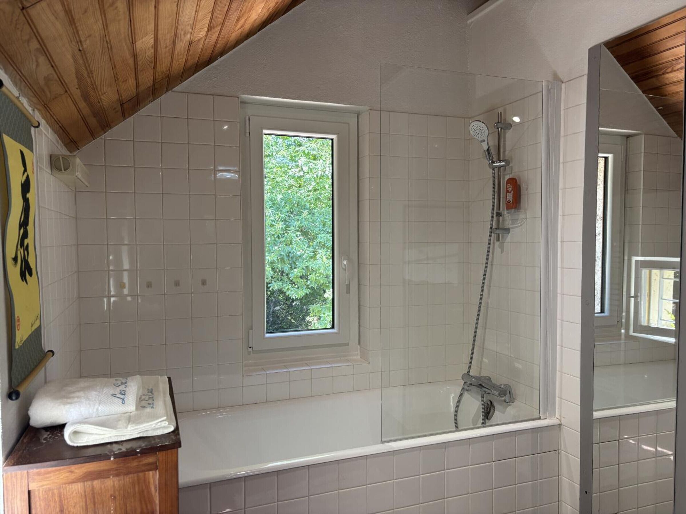 Ein Badezimmer mit Dusche, einem Fenster und einem Handtuch auf der Ablagefläche.