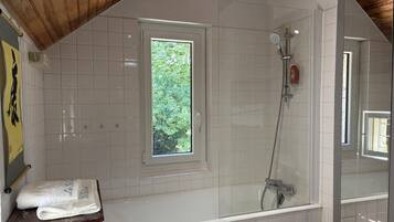 Ein Badezimmer mit Dusche, einem Fenster und einem Handtuch auf der Ablagefläche.