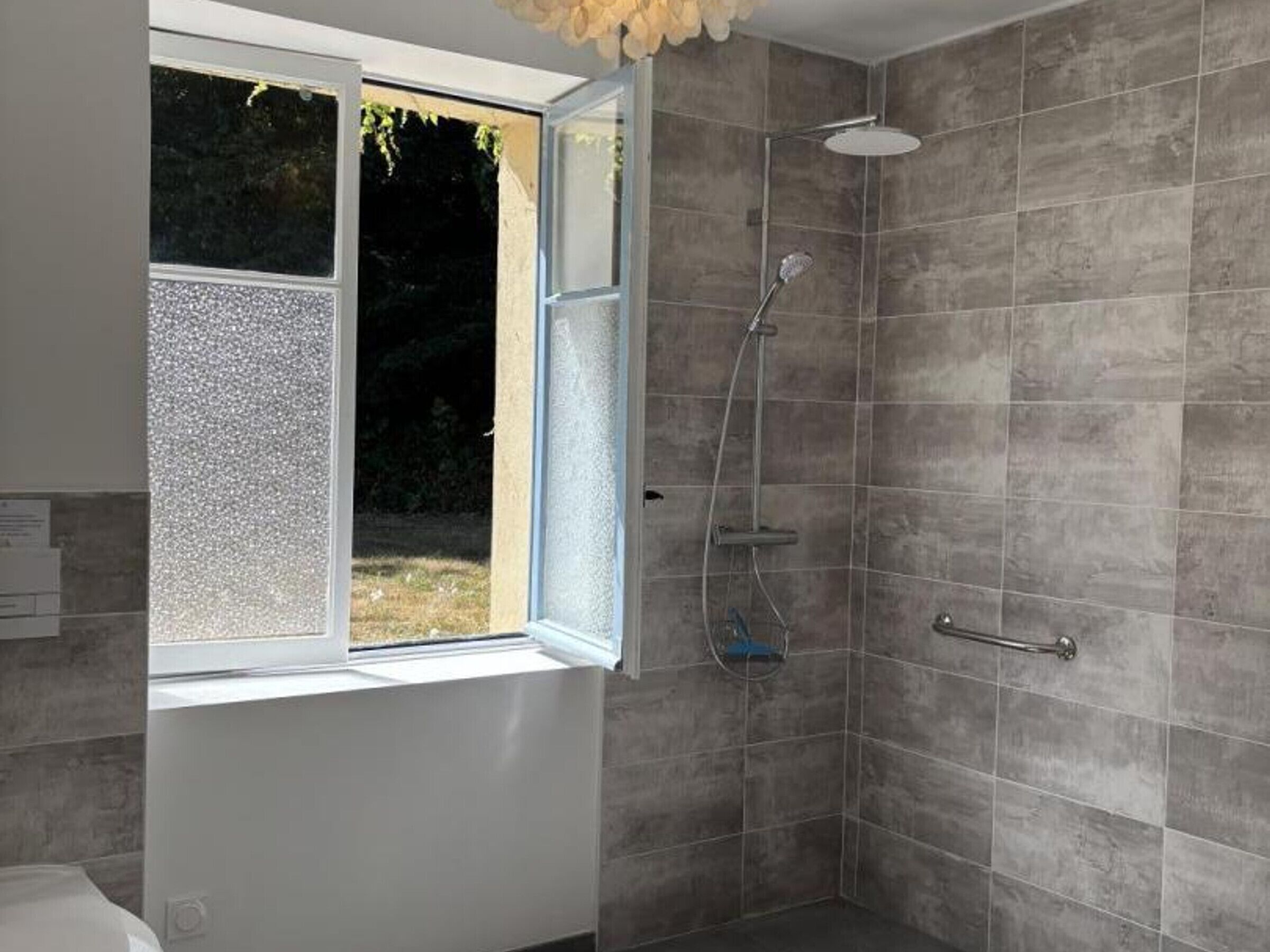 A bathroom with a shower, a window, and a white bathtub.