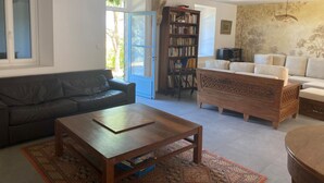 Een woonkamer met een bank, een salontafel, een boekenkast en een kamerkleed met een patroon.