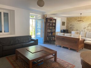 Un salon comprenant un canapé, une table basse, une bibliothèque et un tapis à motifs.
