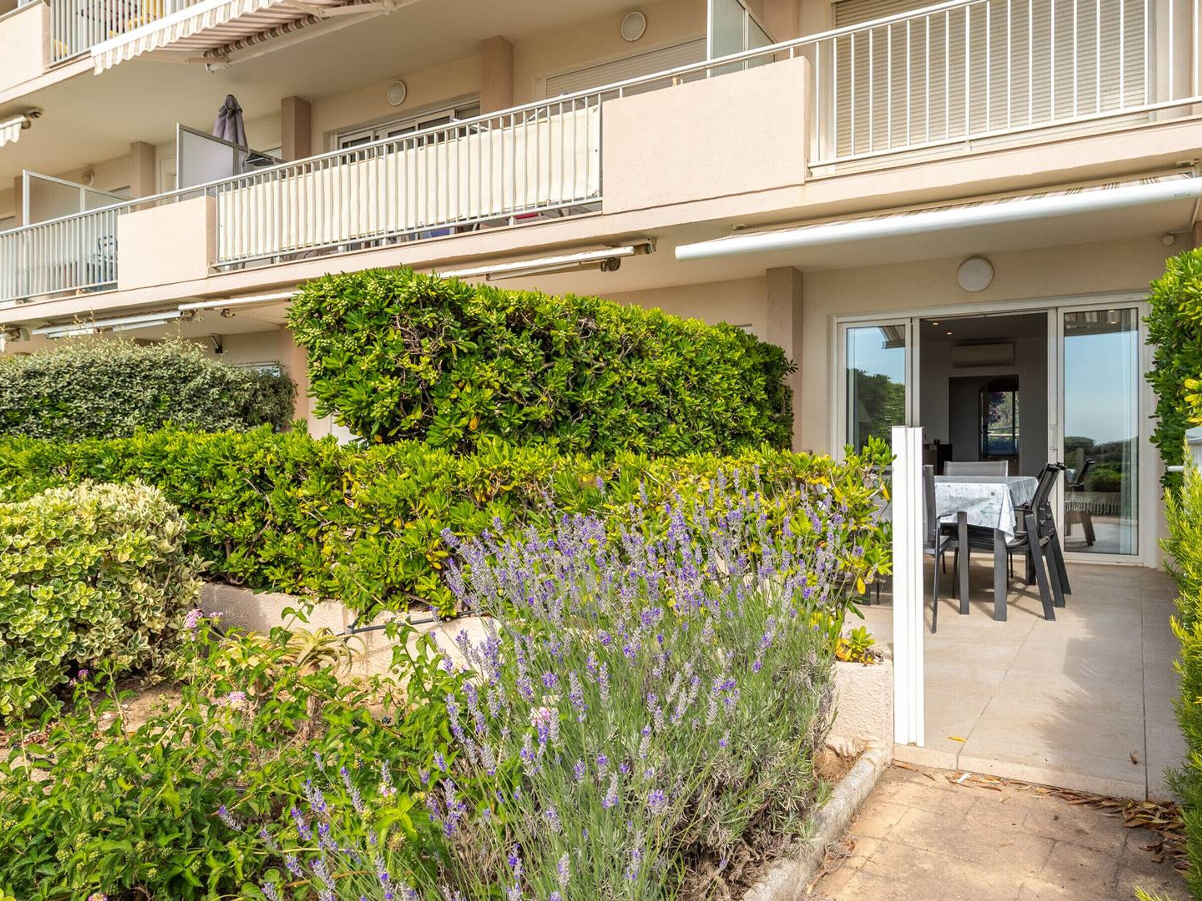 Un immeuble résidentiel doté d’un balcon, d’une terrasse avec mobilier d’extérieur et d’une variété de plantes, notamment de la lavande.